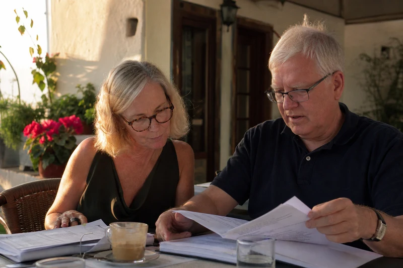 Reviewing tax documents together at a sunny cafe table in Portugal